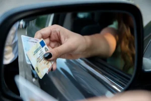 A-womans-hand-reaches-out-of-a-car-window-holding-two-drivers-licenses