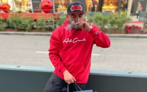 An_Image_from_Carlos_Coronas_Instagram_Account_that_He_Used_to_Recruit_People_for_His_Check-Cashing_Scams_Shows_a_Man_Wearing_Red_and_Black_and_Holding_a_Shopping_Bag_The_Daily_Muck