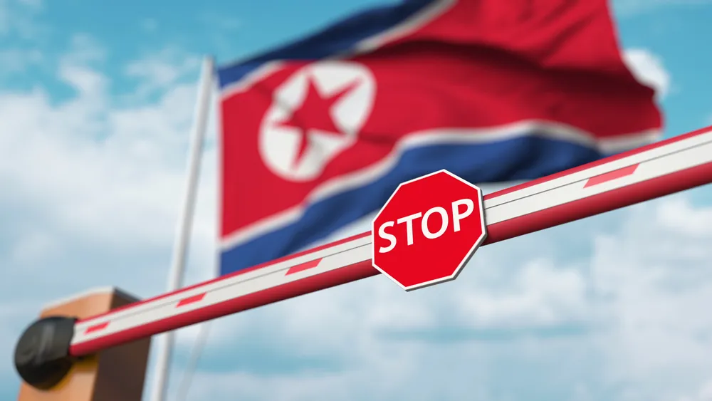 A Sign that Says Stop in Front of a Nrth Korean Flag Represents Tobacco Sanctions Against the Compant Which A Chinese Man and Aco-Conspirators Have been Accused of Breaking - The Daily Muck