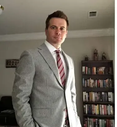 In another photo provided by the FBI, convicted sex assaulter Brian Jeffrey Raymond poses in front of a bookshelf, hands in pockets