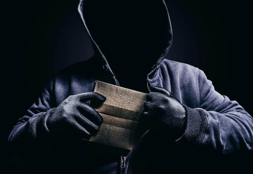 A_Perdon_in_a_Dark_Hoodie_Shoves_a_Package_Into_His_Pocket_Representing_William_Carl_Jackson_Who_Feds_Say_Robbed_Postal_Workers_and_Mailboxes